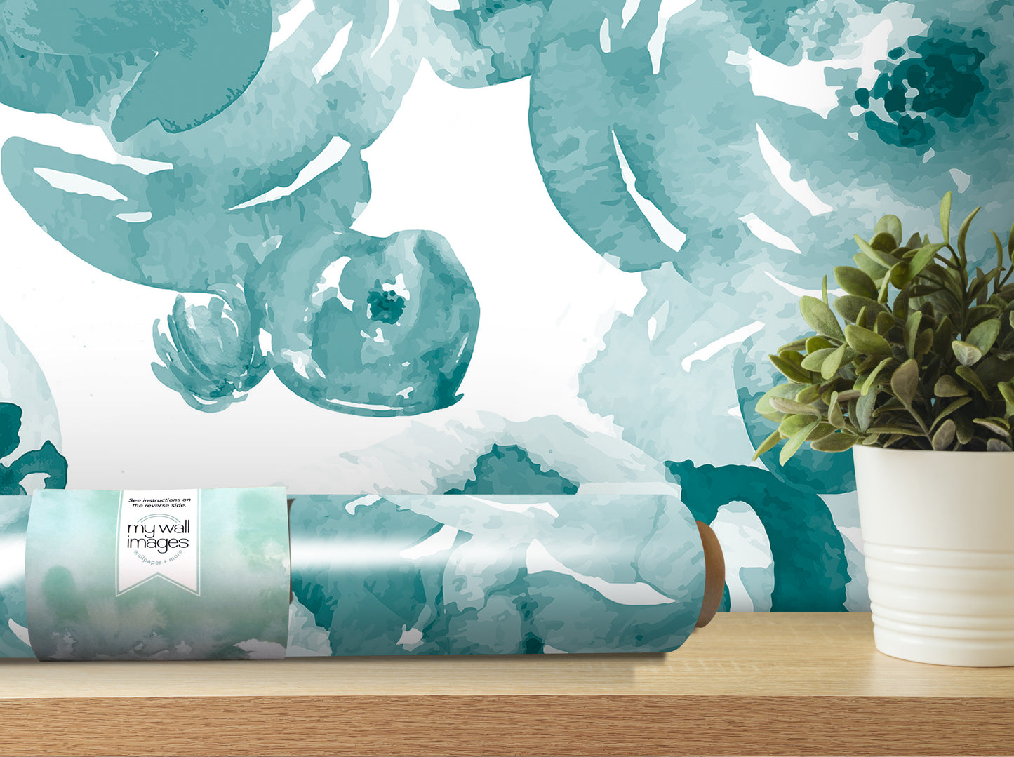 a roll of wallpaper with a watercolor-style floral pattern, placed on a wooden shelf next to a potted plant.