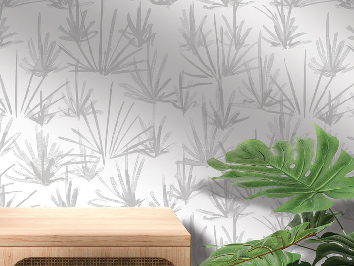 a wall with a pattern of gray and white leaves, and a wooden table is placed in front of the wall.