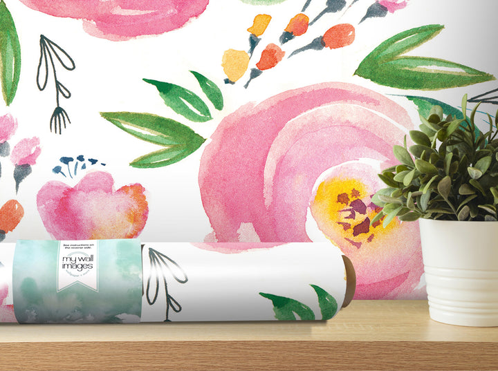 a wallpapered wall with a variety of colorful flowers and leaves, including pink, green, and orange hues. A potted plant is placed on a shelf next to the wallpapered wall, and a roll of wallpaper is visible on a wooden surface.