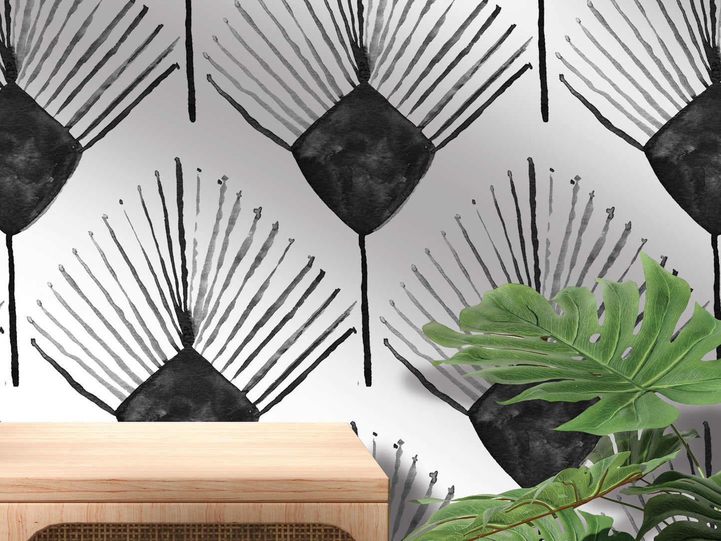 a wall with a repeating pattern of black and white abstract designs, including stylized leaves and flowers. In the foreground, there is a wooden table and a plant, creating a natural and artistic setting.