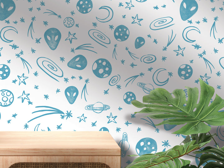 a wall with a pattern of blue and white celestial objects, including planets, stars, and comets, along with a wooden shelf and a plant in the foreground.