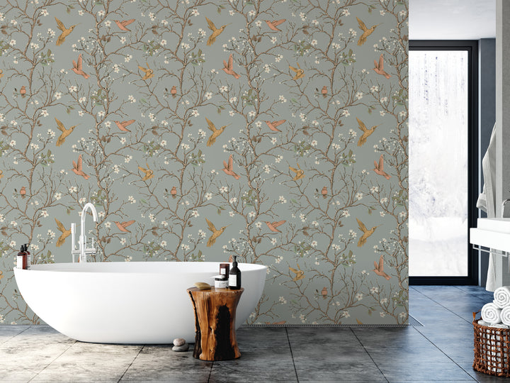 a bathroom with a white freestanding bathtub, a wooden stool, and a window. The walls are adorned with a floral wallpaper pattern, and there are several bottles and a bar of soap placed on the countertop.