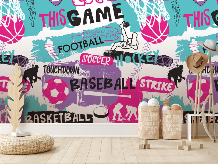 a vibrant and colorful wall mural with various sports-related elements, including a basketball hoop, a soccer ball, and silhouettes of athletes. The wall is adorned with the words "FOOTBALL", "SOCcer", "HOCKEY", "TOUCHDOWN", "BASEBALL", "STRIKE", and "BASKETBALL". In the foreground, there is a wicker basket and a wooden chair, creating a cozy and inviting atmosphere.