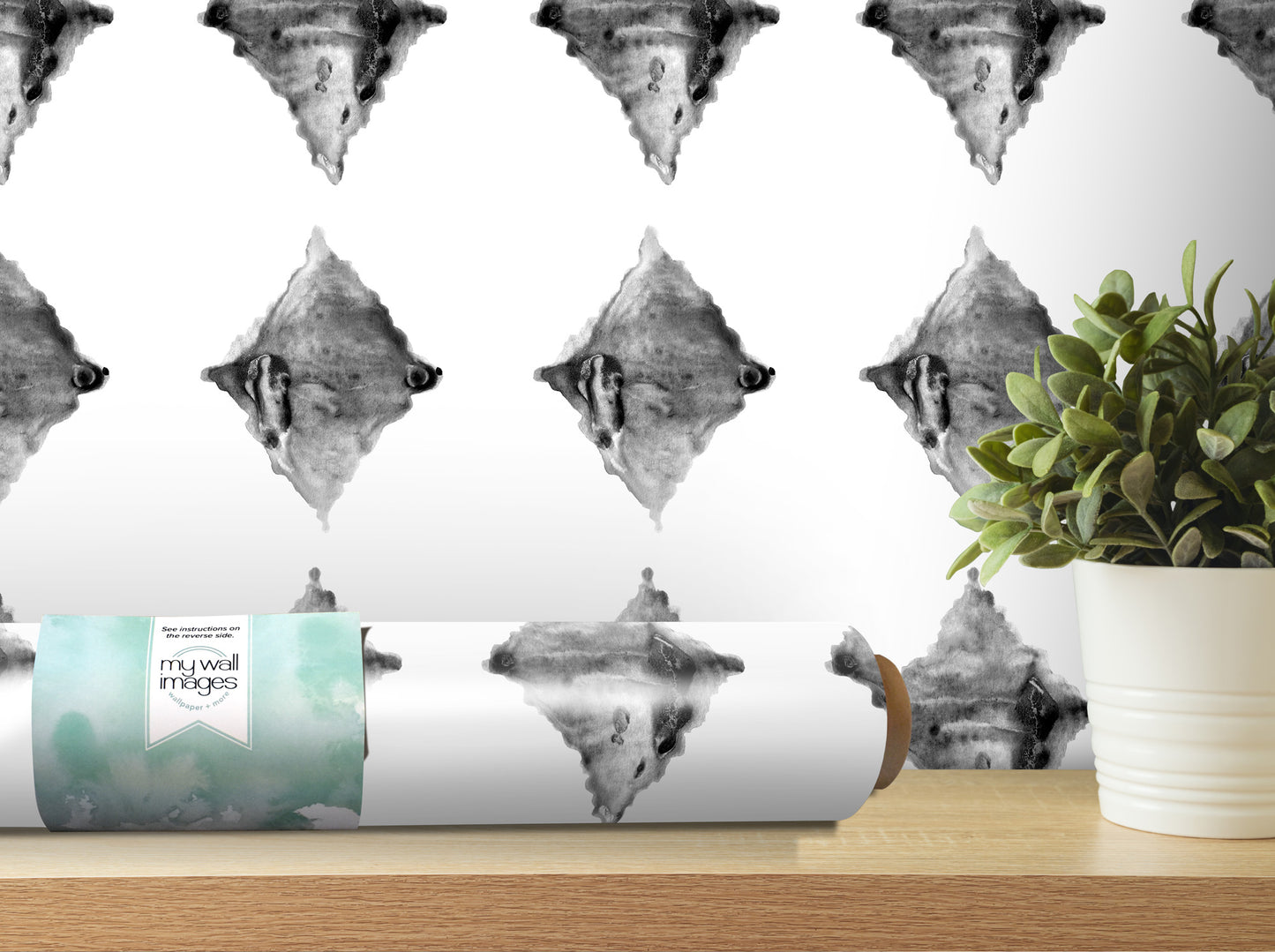 a roll of wallpaper with a repeating pattern of black and white diamond shapes, placed on a wooden shelf next to a potted plant.