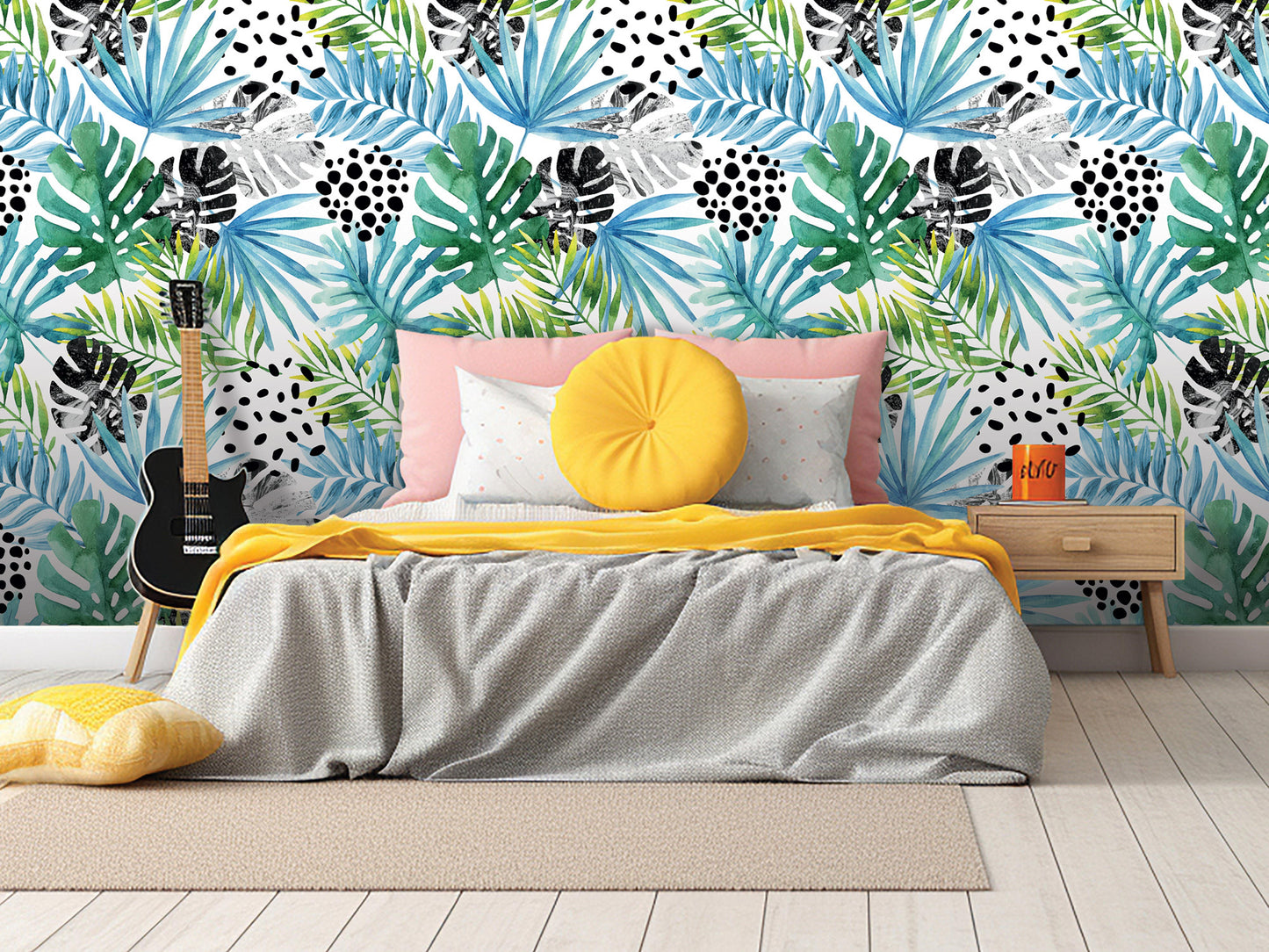 a bedroom with a bed, yellow throw pillow, and a guitar. The wall behind the bed has a tropical leaf pattern in various colors.