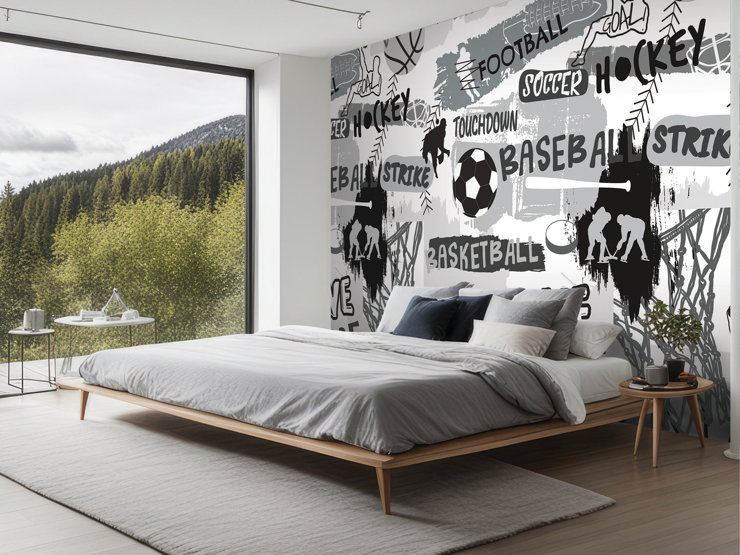 a bedroom with a large wall mural depicting various sports, including hockey, soccer, and basketball. The room has a bed, nightstand, and a large window overlooking a forested area.