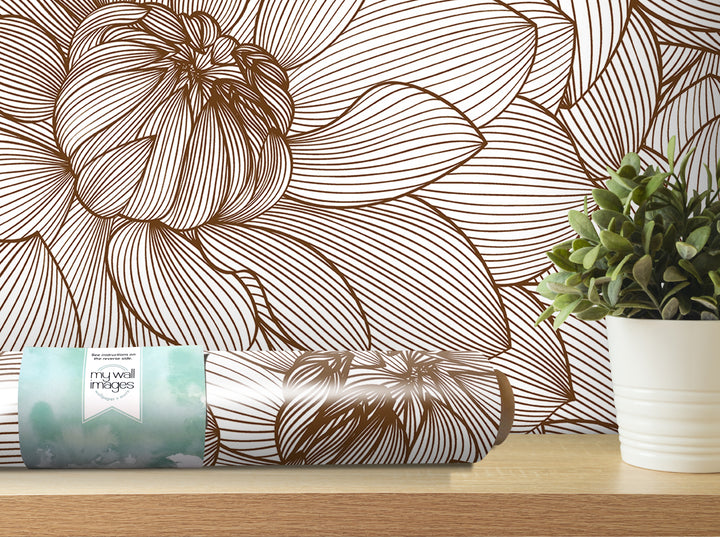 a wallpapered wall with a large brown floral pattern, a potted plant, and a roll of wallpaper with a label.