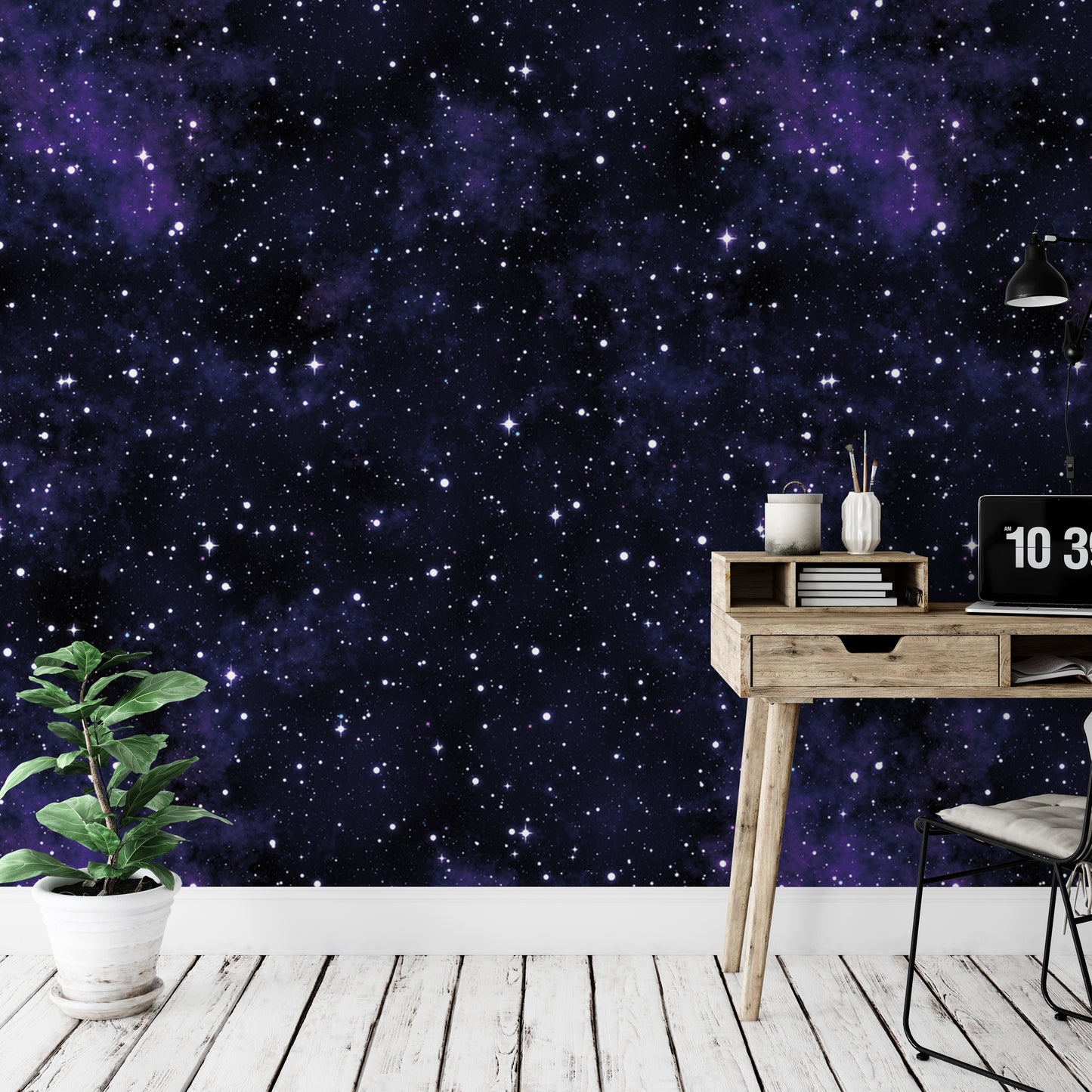 a wooden desk with a laptop, a plant, and a bookshelf against a wall with a starry night sky wallpaper.