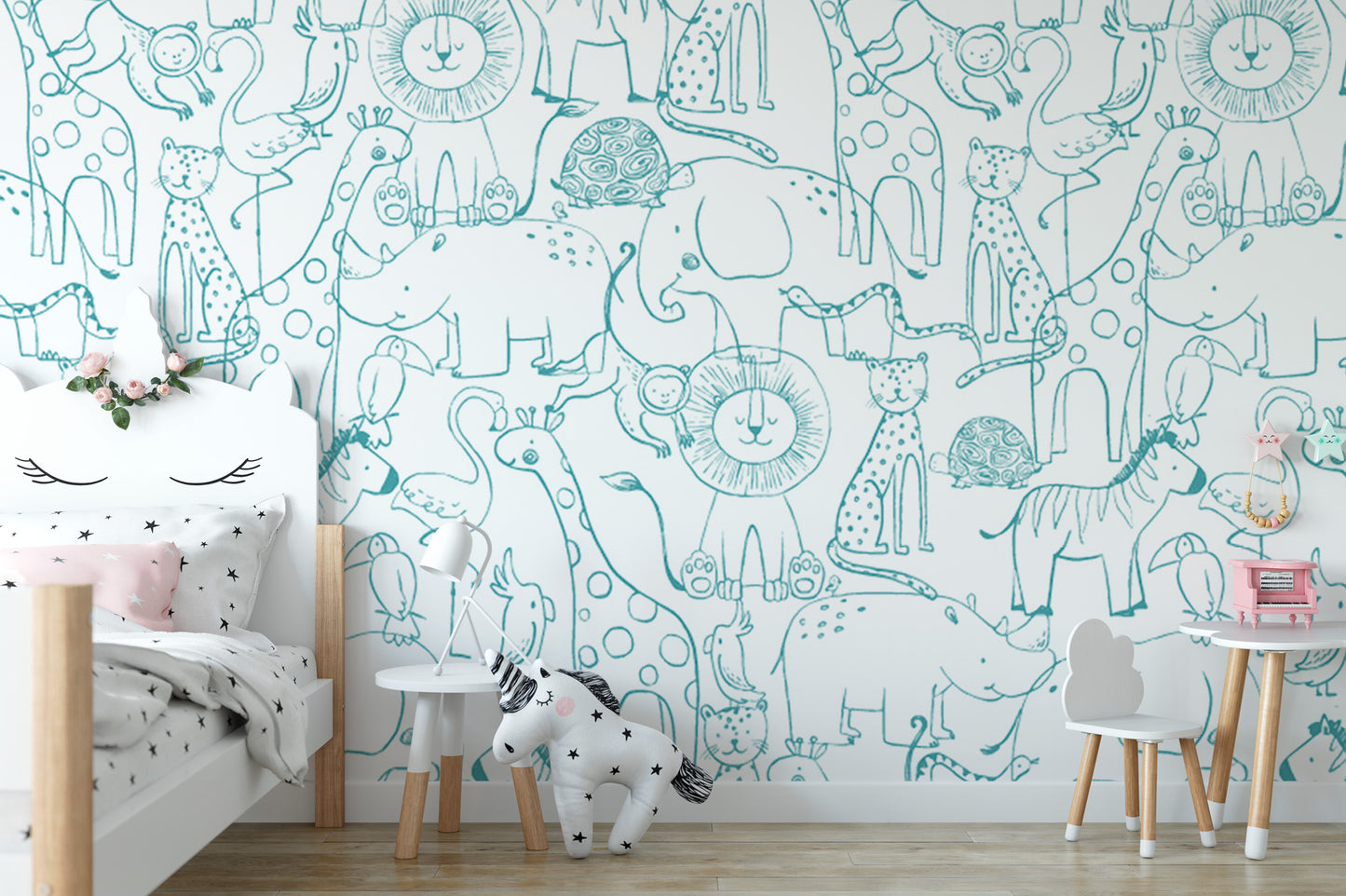 A child's bedroom with a white bed, a small table, and a chair. The walls are covered in a playful wallpaper featuring various cartoon animal illustrations, including giraffes, elephants, lions, and zebras.
