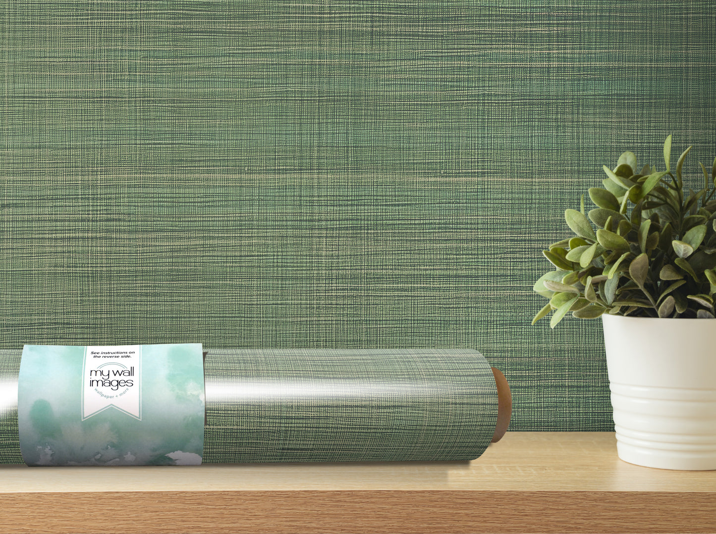a roll of wallpaper with a green and white pattern, placed on a wooden shelf next to a potted plant.