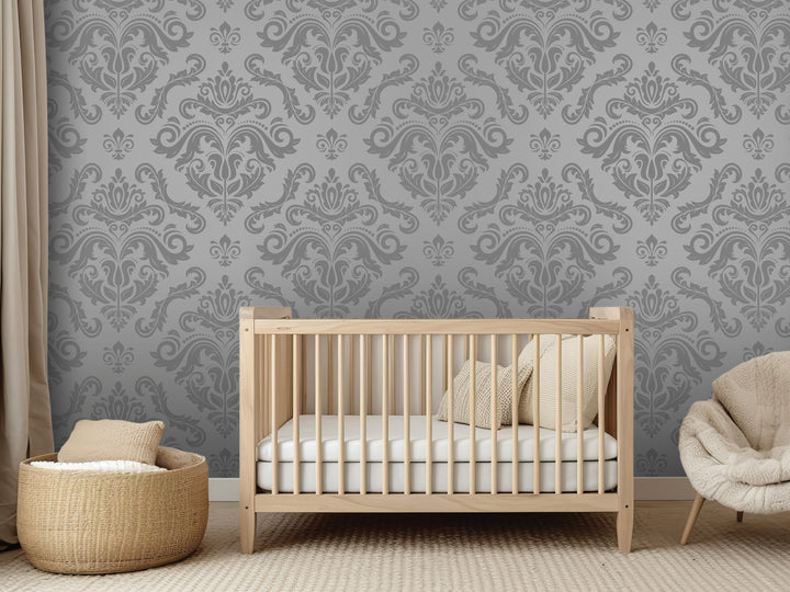a modern nursery with a wooden crib, a beige chair, and a woven basket. The crib is positioned against a gray wall with a repeating pattern of floral designs.