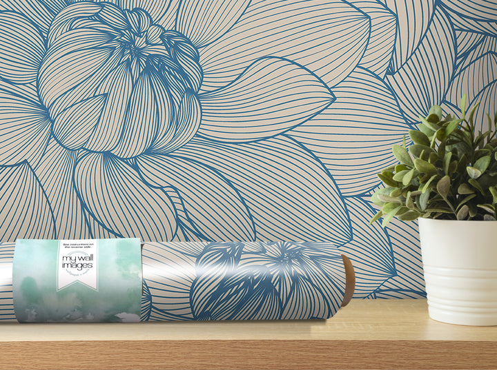 a blue and white floral wallpaper on the wall, with a potted plant and a roll of wallpaper paper on a shelf in the foreground.