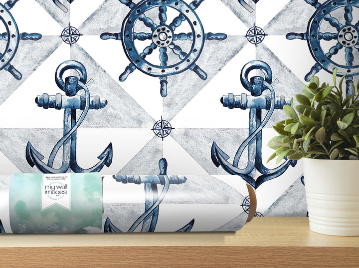 a wallpapered wall with a repeating pattern of blue anchors and a ship's wheel, along with a potted plant and a roll of wallpaper in the foreground.