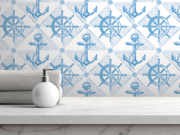 a bathroom setting with a white countertop, a white soap dispenser, and a gray towel. The backdrop is a wall with a repeating pattern of blue anchors and ship wheels, creating a nautical theme.