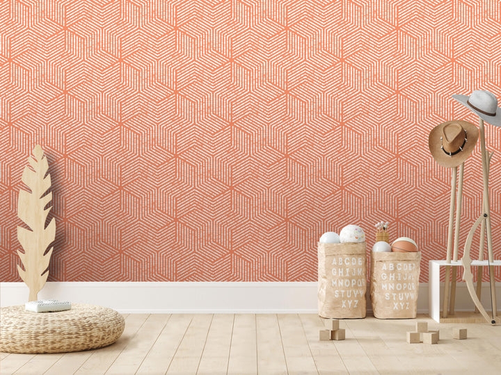 a room with a geometric orange and white patterned wallpaper on the wall. The room has a wooden floor and a wicker basket on the floor. There are also two wooden stools and a hat rack in the room.