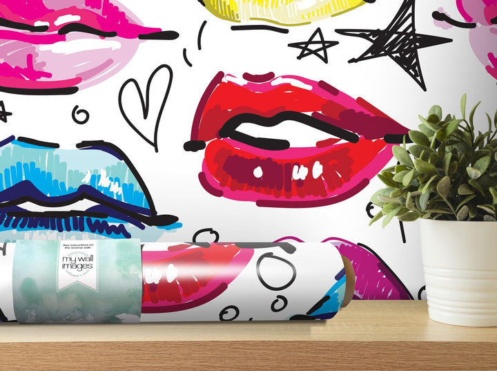 a vase with a plant in it next to a wall with lipstick on it