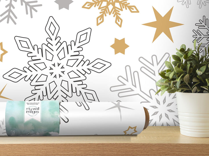 a white vase filled with a green plant next to a white snowflake wall