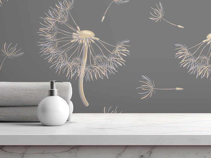 a white soap dispenser on a white marble countertop, with a gray towel and a white bottle of lotion nearby. The background has a gray wall with a repeating pattern of dandelion-like designs.