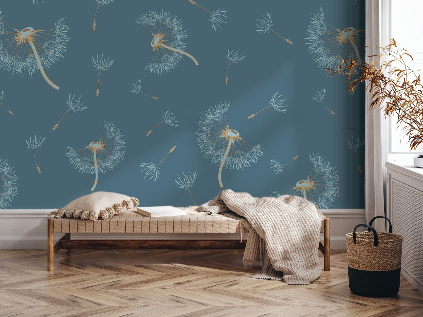 a cozy living room with a blue wall adorned with a repeating pattern of dandelions. In the center of the room, there is a wooden bench with a white pillow on it. To the right of the bench, there is a woven basket. A potted plant is also present in the room, adding a touch of greenery to the space.