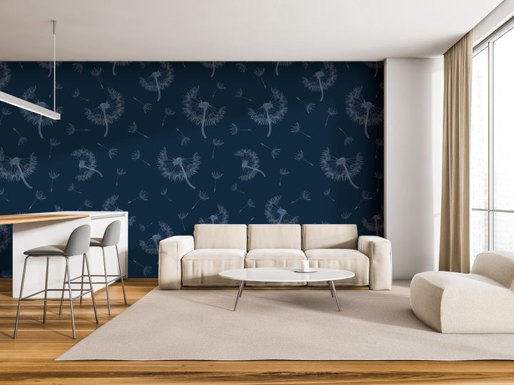 a modern living room with a blue wall featuring a repeating pattern of dandelions. The room is furnished with a white sofa, a round coffee table, and a barstool. The overall design and color scheme create a serene and inviting atmosphere.