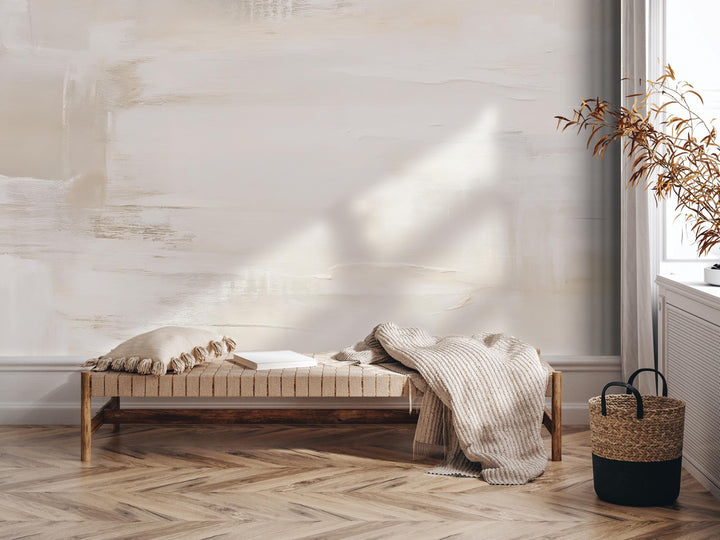 a minimalist living space with a wooden bench, a woven basket, and a plant. The bench is positioned against a white wall with a textured paint design.
