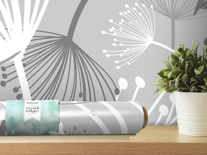 a gray and white abstract floral pattern on the wall behind a wooden shelf, with a potted plant and a roll of wallpaper on the shelf.