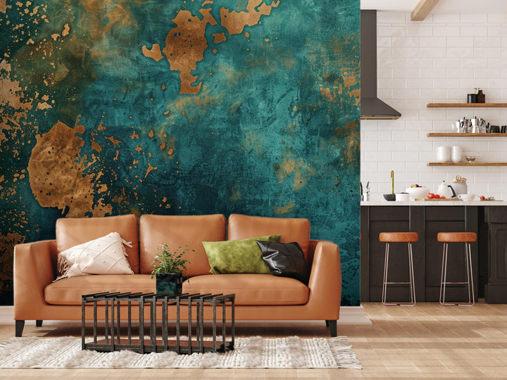 a modern living room with a large, vibrant green and gold textured wall behind a brown leather sofa. The sofa is adorned with two throw pillows, one green and one black. In front of the sofa, there is a black coffee table with a plant on it. The room also includes a kitchen area with a countertop and stools, as well as a rug on the floor.
