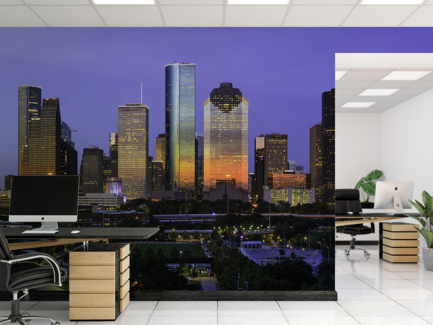 a modern office space with a large mural of a city skyline at night. The office features a desk with a computer, a chair, and a plant, creating a professional and comfortable work environment.