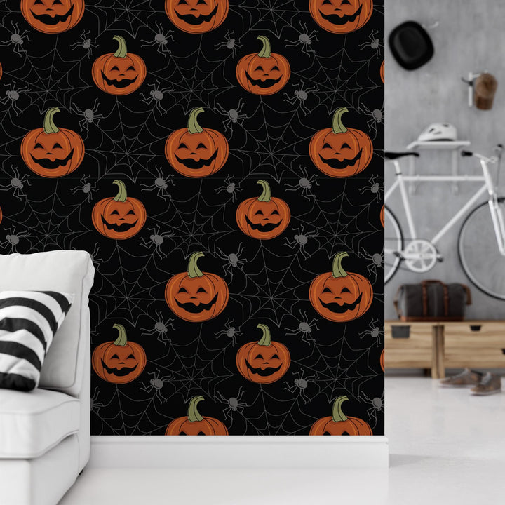 a wall with a repeating pattern of Halloween pumpkins and spiders against a black background.