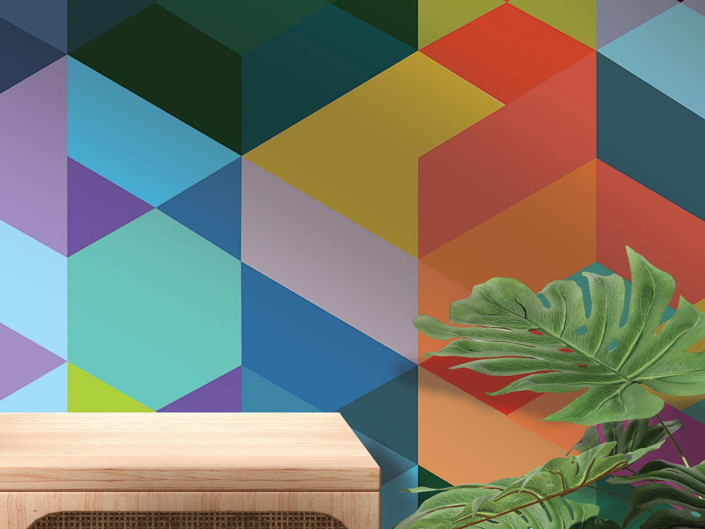 a vibrant geometric pattern on the wall behind a wooden table, with a large green leaf plant in the foreground.