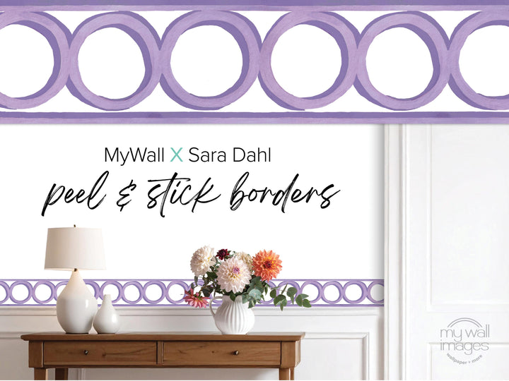 a wooden table with a vase of flowers, a lamp, and a purple border with a repeating circular pattern.