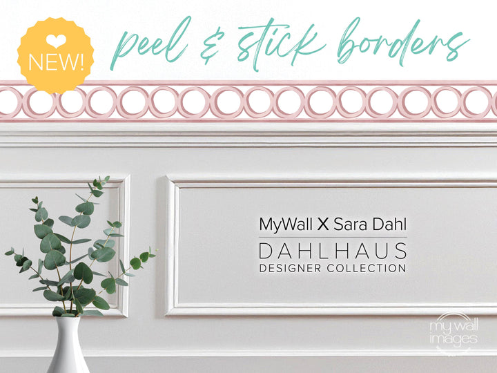 a white wall with a decorative border, a vase of greenery, and text that reads &quot;MyWall X Sara Dahl Dahlhaus Designer Collection&quot;.