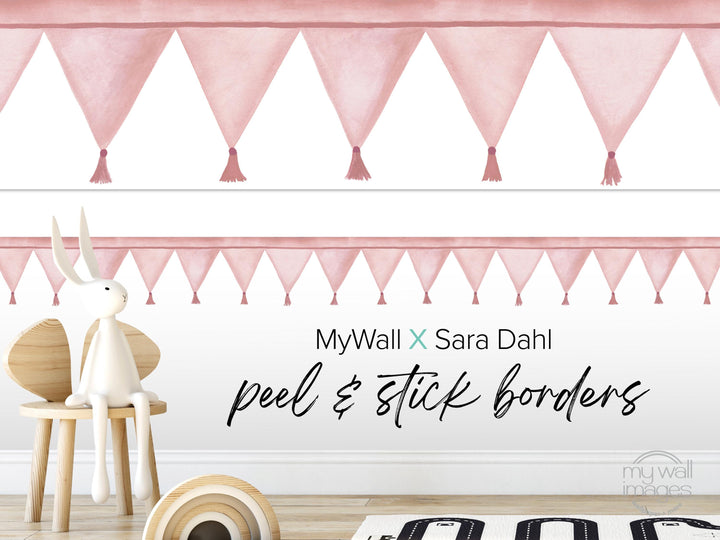 a pink and white decorative border with tassels, a white stuffed rabbit sitting on a wooden chair, and a wooden toy car on the floor.
