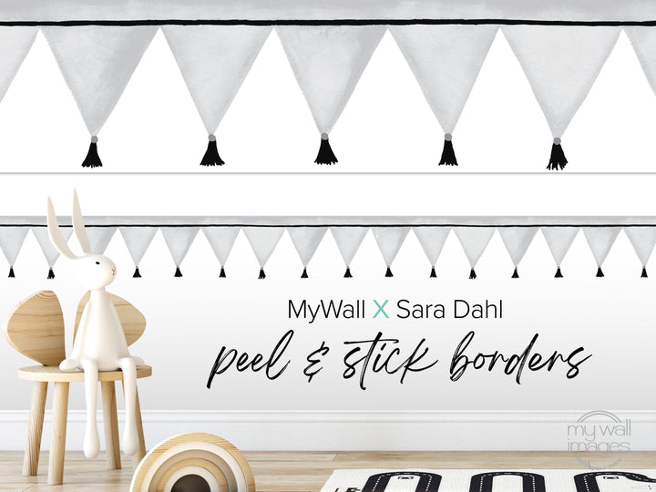 a white rabbit sitting on a wooden chair, with a wall decorated with black and white tassels above it. The wall also has a text overlay that reads &quot;MyWall X Sara Dahl peel & stick borders&quot;.